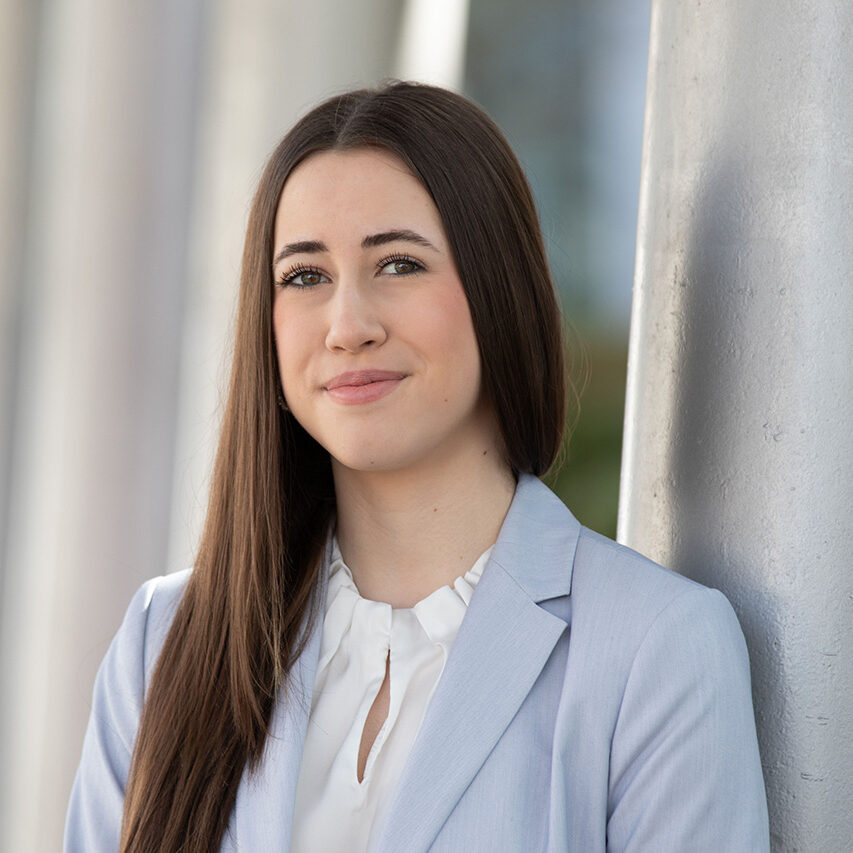 Portrait Auszubildende Hannah Wöß, lächelnd, an helle Säule gelehnt (Foto: © photoprisma)